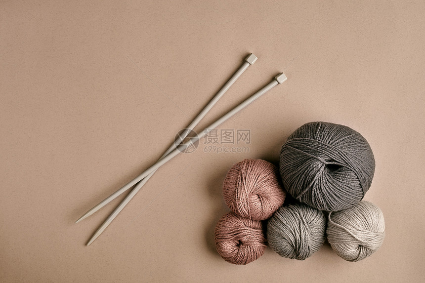 由灰色纱线毛衣和针织特写线针织而成编织作为一种爱好米色背景上的针织配件顶视图静物复图片