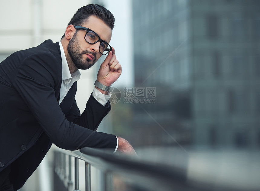 穿西装戴眼镜的英俊商人在仰着阳台看图片