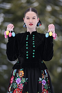 穿着传统服装彩色东方鸡蛋的美丽的斯洛瓦克图片