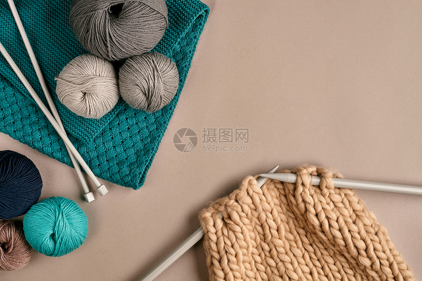 灰色和绿松石球羊毛和针织在米色背景上的针织作为一种针线活五颜六色的毛线球和织针顶视图静物复图片