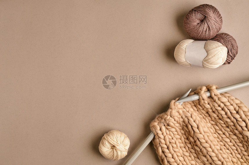 白色和棕色球毛和针织在米色背景上的针织作为一种针线活五颜六色的毛线球和织针顶视图静物复图片