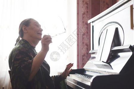 坐在钢琴前唱一首歌的老妇图片