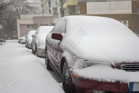 冬日城市街道上被雪覆盖的汽车图片