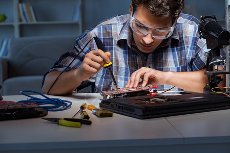 在主板上焊接电气零件的年轻维修技术员图片