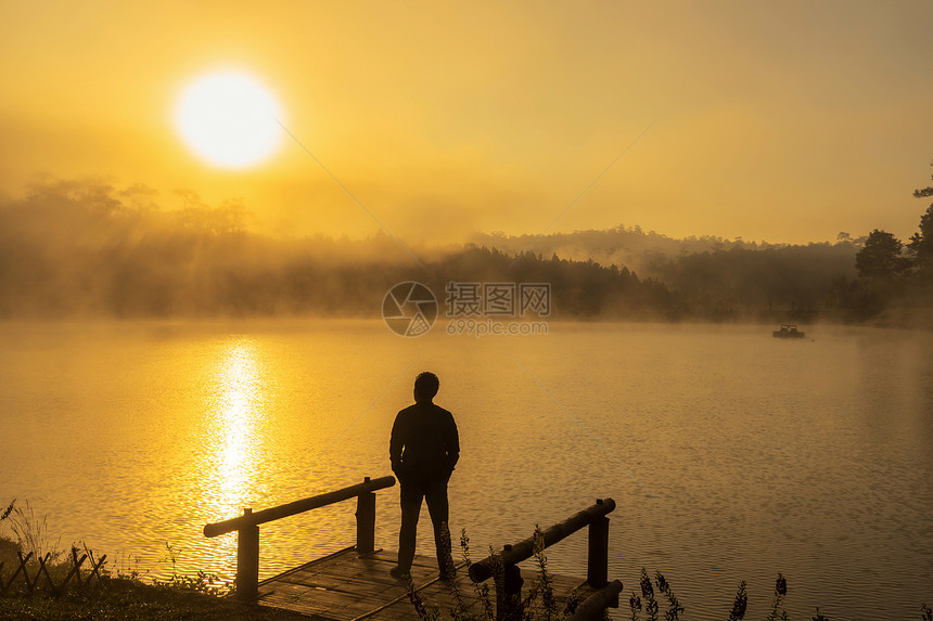 日出时分站在船屋河湖上的剪影抑郁男子图片