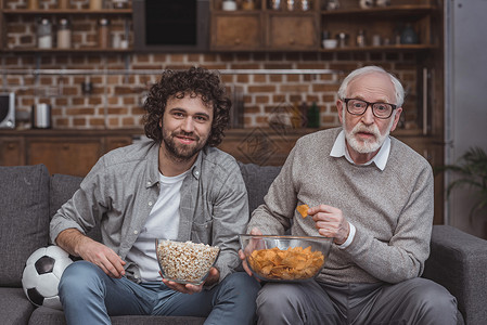 成年儿子和年长父亲在家看有爆米花和薯图片