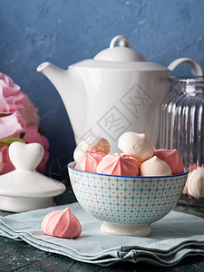 蓝色背景陶瓷碗中的粉色和白色蛋白甜饼图片