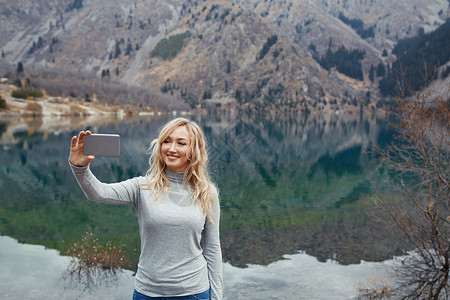 微笑的女人在高山湖边自拍图片