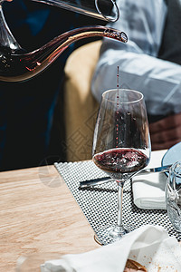 在品酒会上供应餐桌品酒师将红酒从醒酒器背景图片