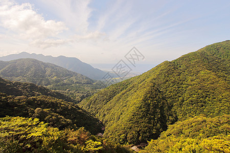 从通往日本ShirataniUnsuikyoRavine公园的公路上看到北面大片绿山和雅库岛海滨背景图片
