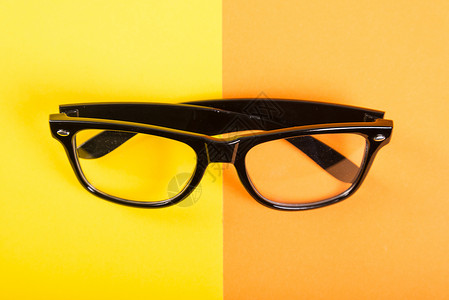 一副黄色和橙色背景的黑色眼镜图片