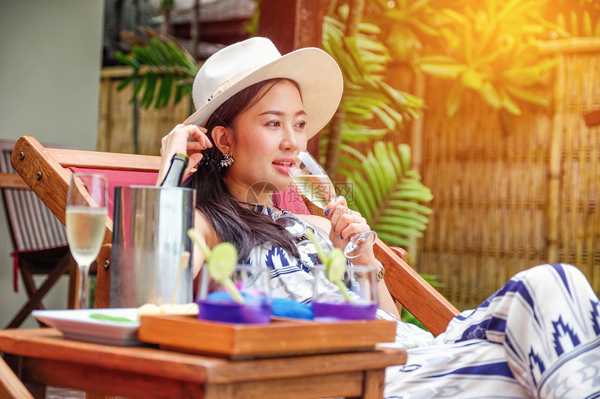 美丽的年轻女子躺在甲板椅上手里拿图片