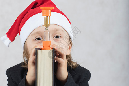 圣诞老人的帽子和黑色古典夹克的四年男孩在圣诞老人的帽子和黑书的四年的特写镜头男孩坐背景图片