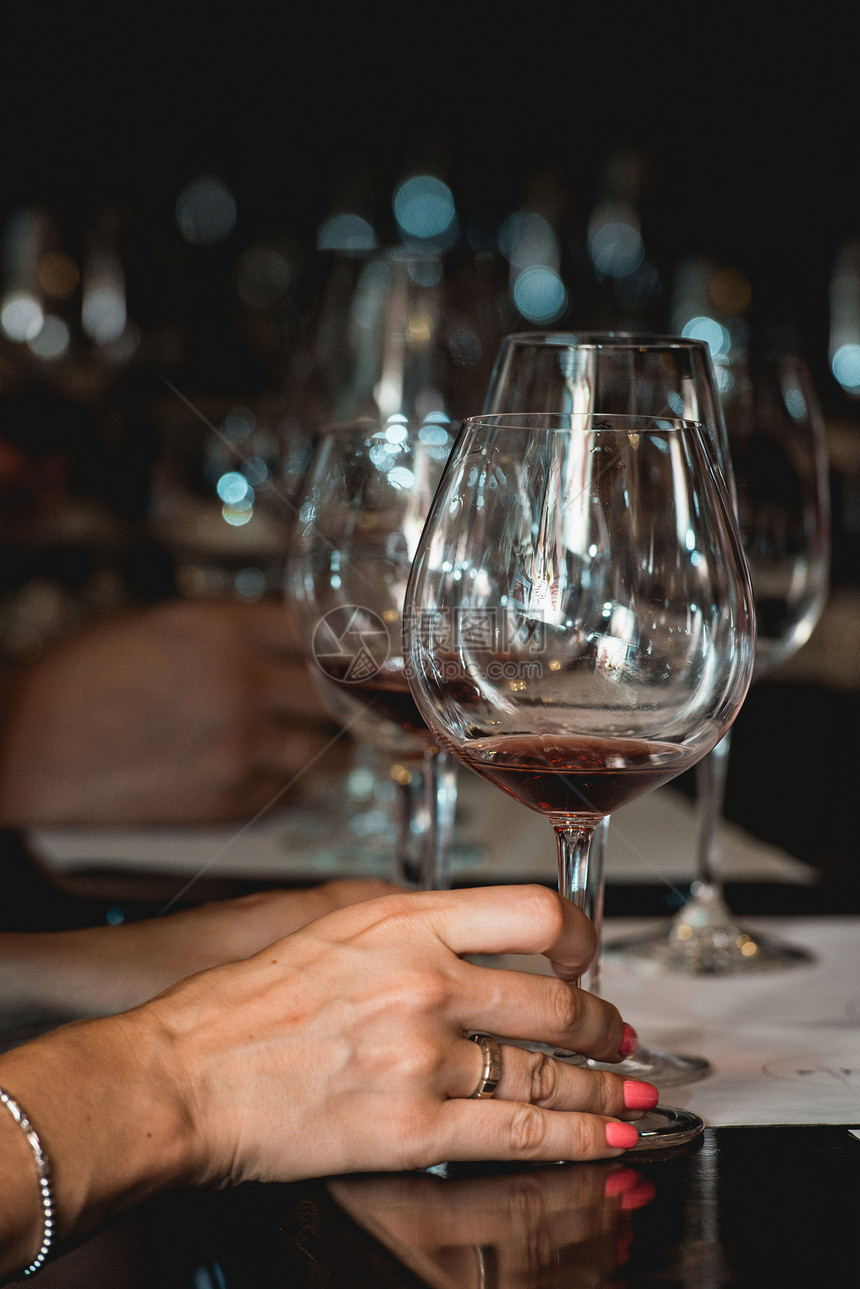 女人拿着一杯红酒品酒时桌上的眼镜人们会考虑葡萄酒的颜色并尝试在不同的玻璃杯中图片