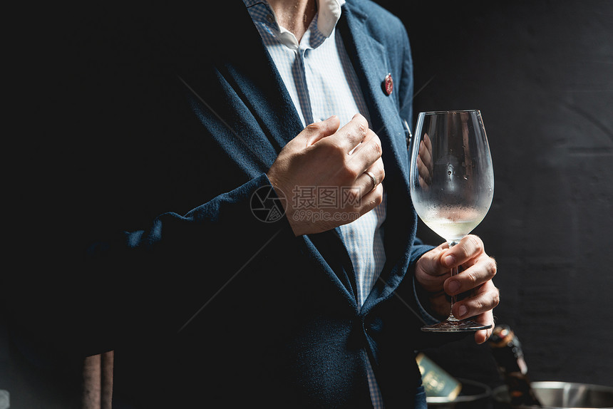 男人拿着一杯红酒品酒时桌上有很多不同的酒杯人们会考虑葡萄酒的颜色并尝试在不同的玻璃杯中图片