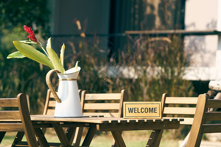 欢迎牌在草坪中间放一张带椅子的木桌用复古花瓶装饰用作背景室内装饰概念图片