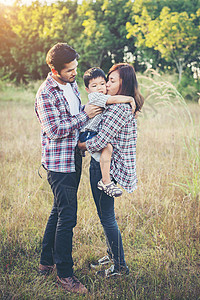 快乐的年轻家庭在绿色自然公园外面共度时光图片