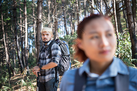 在松树林中徒步旅行情侣背包客的特写图片