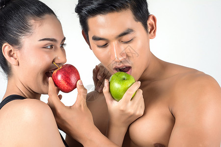 年轻快乐的运动夫妇男女在吃健康的食物孤立在白图片