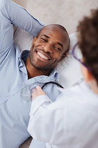 快乐的欢乐喜悦的男人在笑和孩子听他当医生的时候躺着时图片