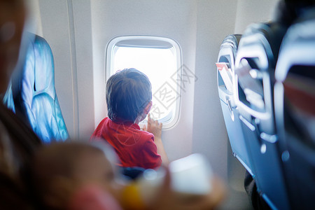 小男孩在飞机行期间看着飞机窗外图片