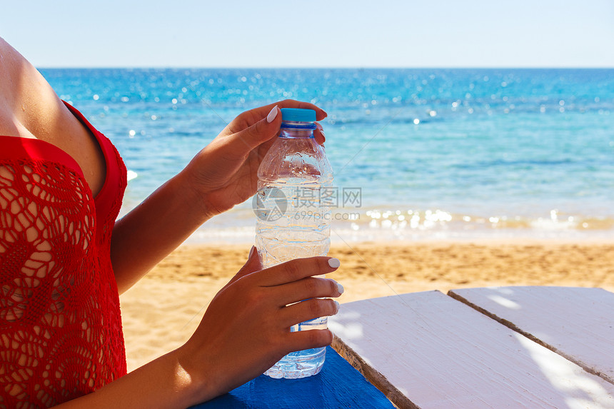 女人手在海滩上户外打开一瓶水图片