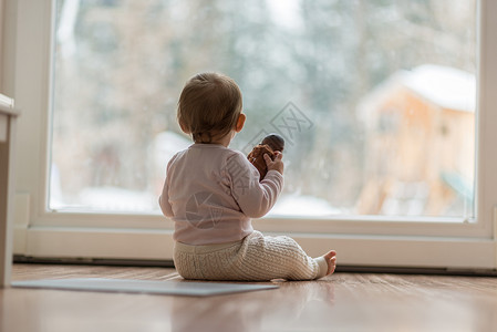 小女婴坐在大视窗前的木地板上图片