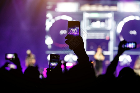 在演唱会上用智能手机拍手的脚影在舞台上图片