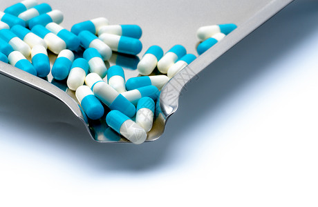 白色背景上的蓝色和白色胶囊药丸和药物托盘图片