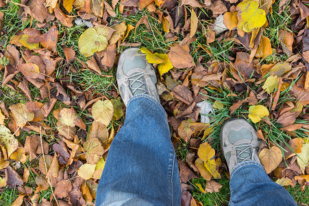 身穿牛仔裤和运动鞋的人在秋天的地上踩脚图片