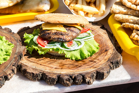 鸡肉奶酪和木板上新鲜蔬菜的开胃汉堡图片