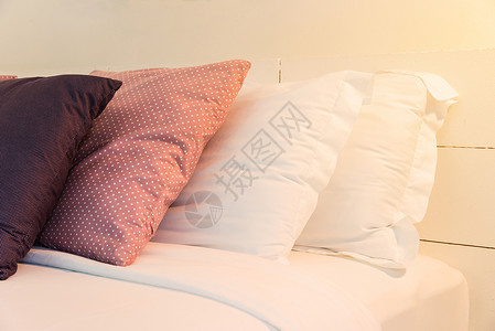 在床上和白砖墙上堆放靠背枕头和白枕头图片