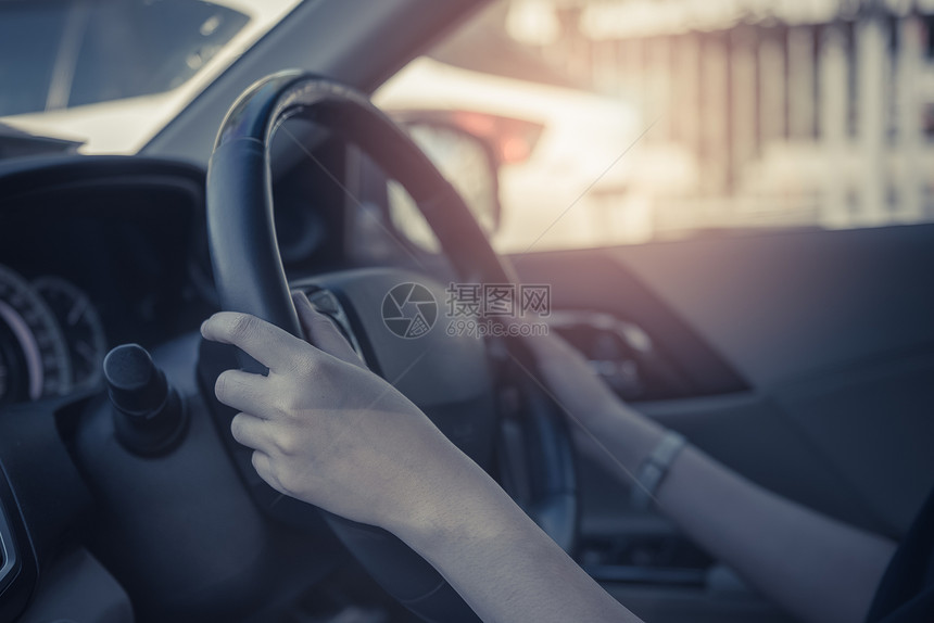 青年妇女在路上驾驶汽车时手握方向盘图片