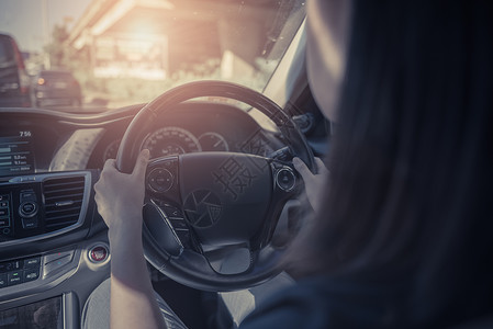 在路上驾驶汽车的年轻妇女手牵着方向盘在一辆汽车旁驾驶车图片