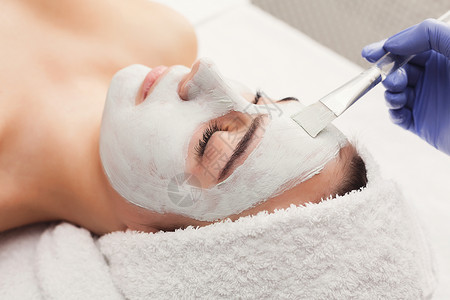 脸部面具温泉美容治疗皮肤护理妇女通过美容师在SPA沙龙上做面部按图片
