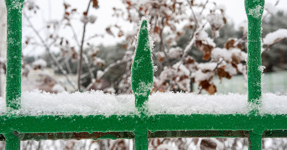 第一次下雪的绿铁栅栏的一部分图片