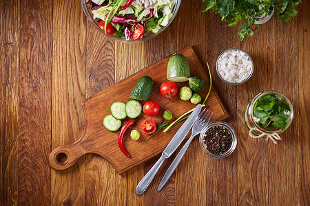 新鲜蔬菜沙拉和成熟蔬菜在木制背景上的切菜板上图片