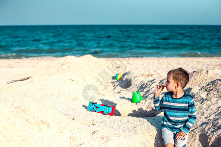一个男孩在沙滩上玩耍一个孩子坐在沙滩上孩子在海边运图片
