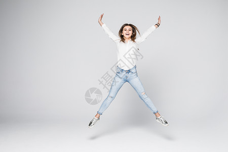 微笑的年轻女子在空中跳跃与高举拳头在图片
