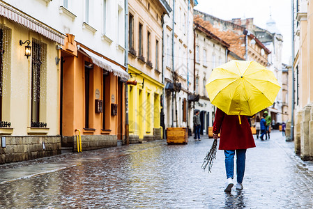 穿着红色大衣和黄色雨伞的女子在图片