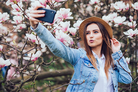 穿暑假帽的年轻美女在花木兰树附图片