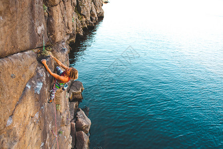 女孩登山者爬上水面的岩石户外活图片