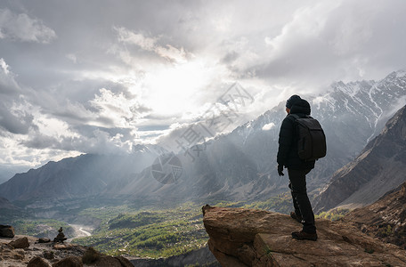 一个人背着包站在山峰顶上图片