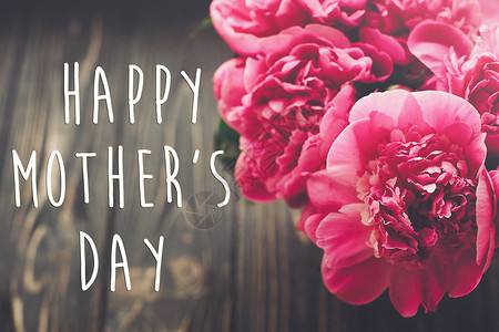 母亲节快乐文本上粉红色牡丹花束在质朴的深色木制背景光图片