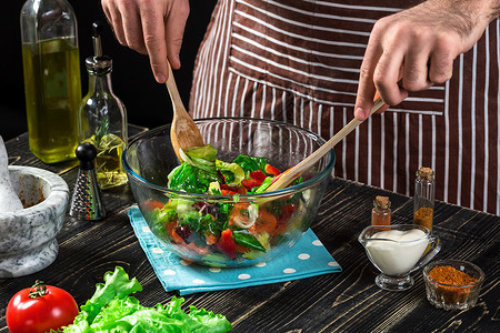 男人在木桌上准备新鲜蔬菜沙拉烹饪美味和健康的食物在黑色背景上素食健图片