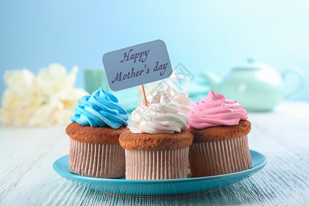 美味的纸杯蛋糕和尖嘴小蛋糕上面写着欢乐母亲在背景图片