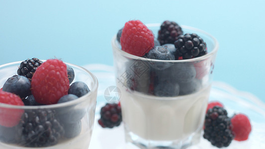 眼镜与希腊酸奶和浆果蓝色背景的极简主义食物意式奶冻配草莓图片