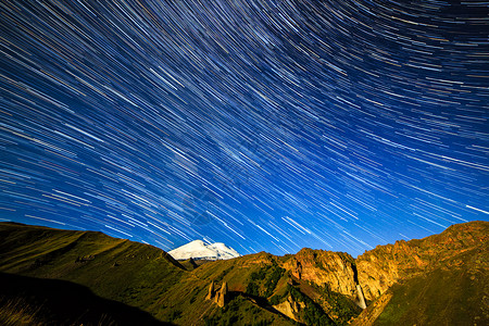 星在厄尔布鲁士山上空画出褪色的线条和云朵夜景俄罗斯星的线图片