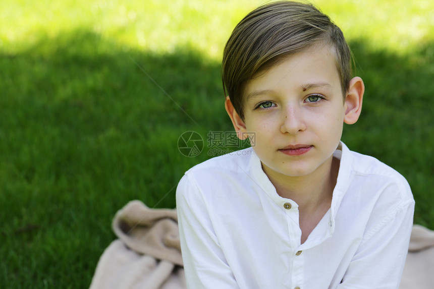 金发男孩在绿草地上穿着白衣的图片