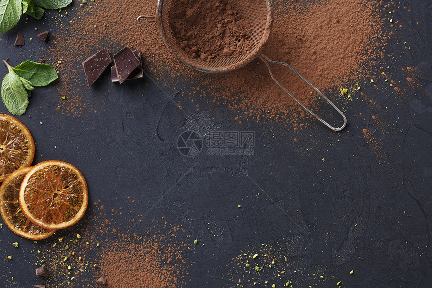 烹饪甜美的背景筛子中的可粉切碎的巧克力棒橙子柚和黑色石板上的薄荷叶布朗尼食谱的样机顶视图片